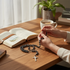 Jefgo traditional religious prayer rosary beads with dark metallic finish held by hands on a wooden desk